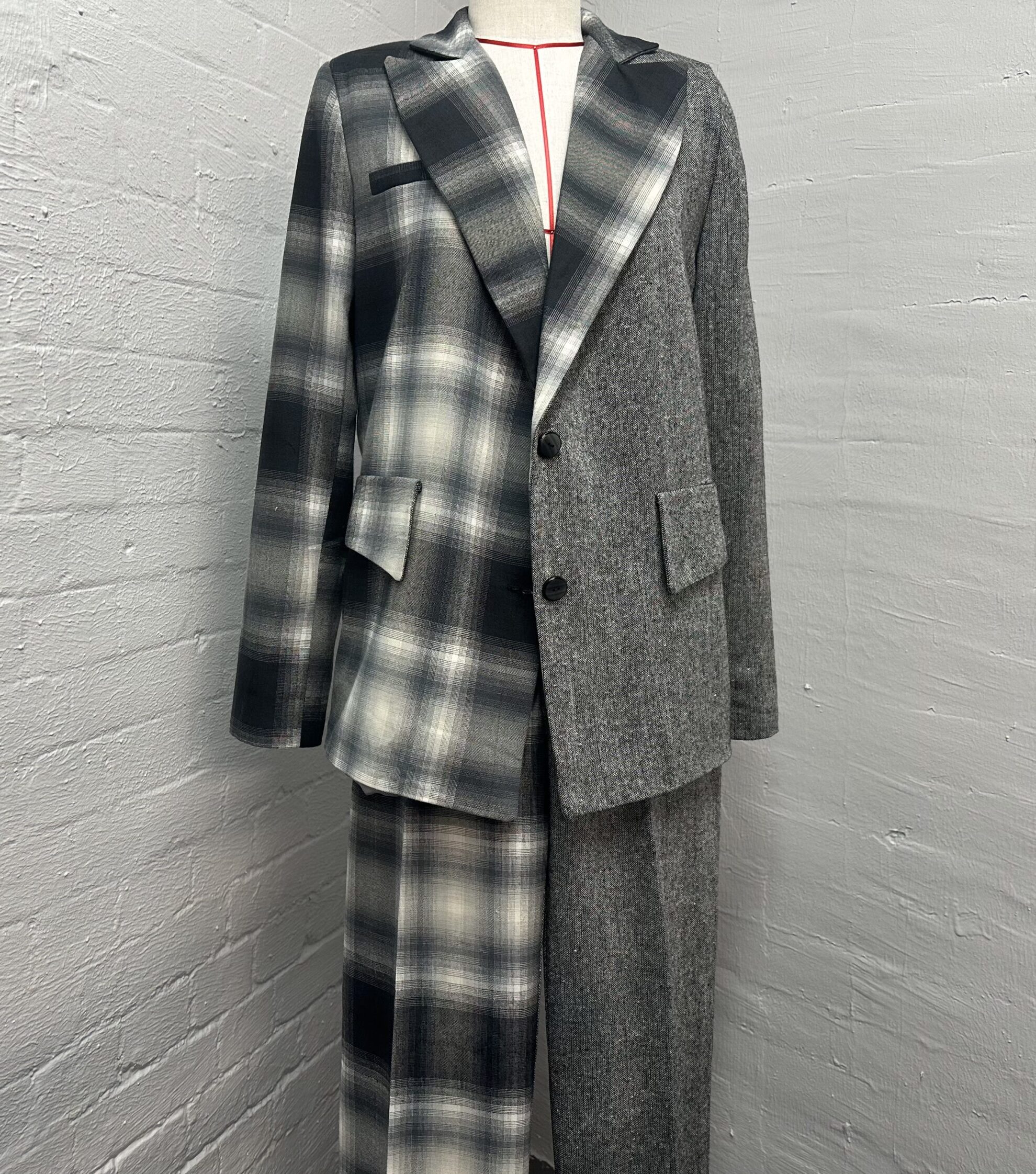 A bespoke women's suit by K&K Couture, featuring a sophisticated two-tone grey design with geometric paneling and white contrast stitching