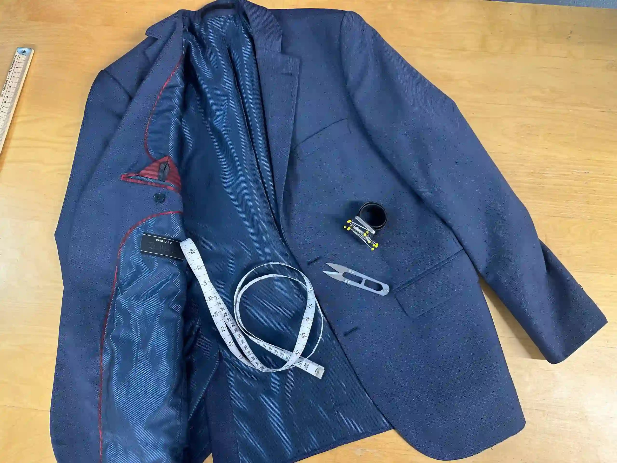 Jacket Alterations: A tailor pinning the sleeve of a blazer during a fitting in London.